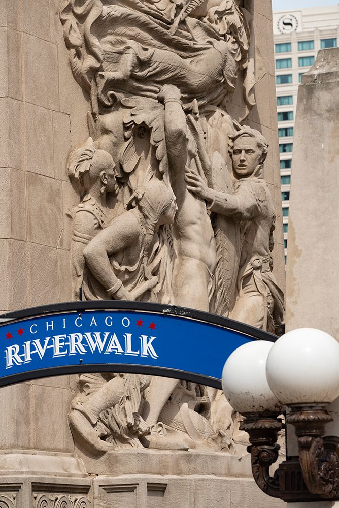 Riverwalk signage along the Chicago River in downtown Chicago with Michigan Avenue bas-relief